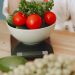 Colorful fresh vegetables including tomatoes and cucumbers on a kitchen scale for healthy eating.
